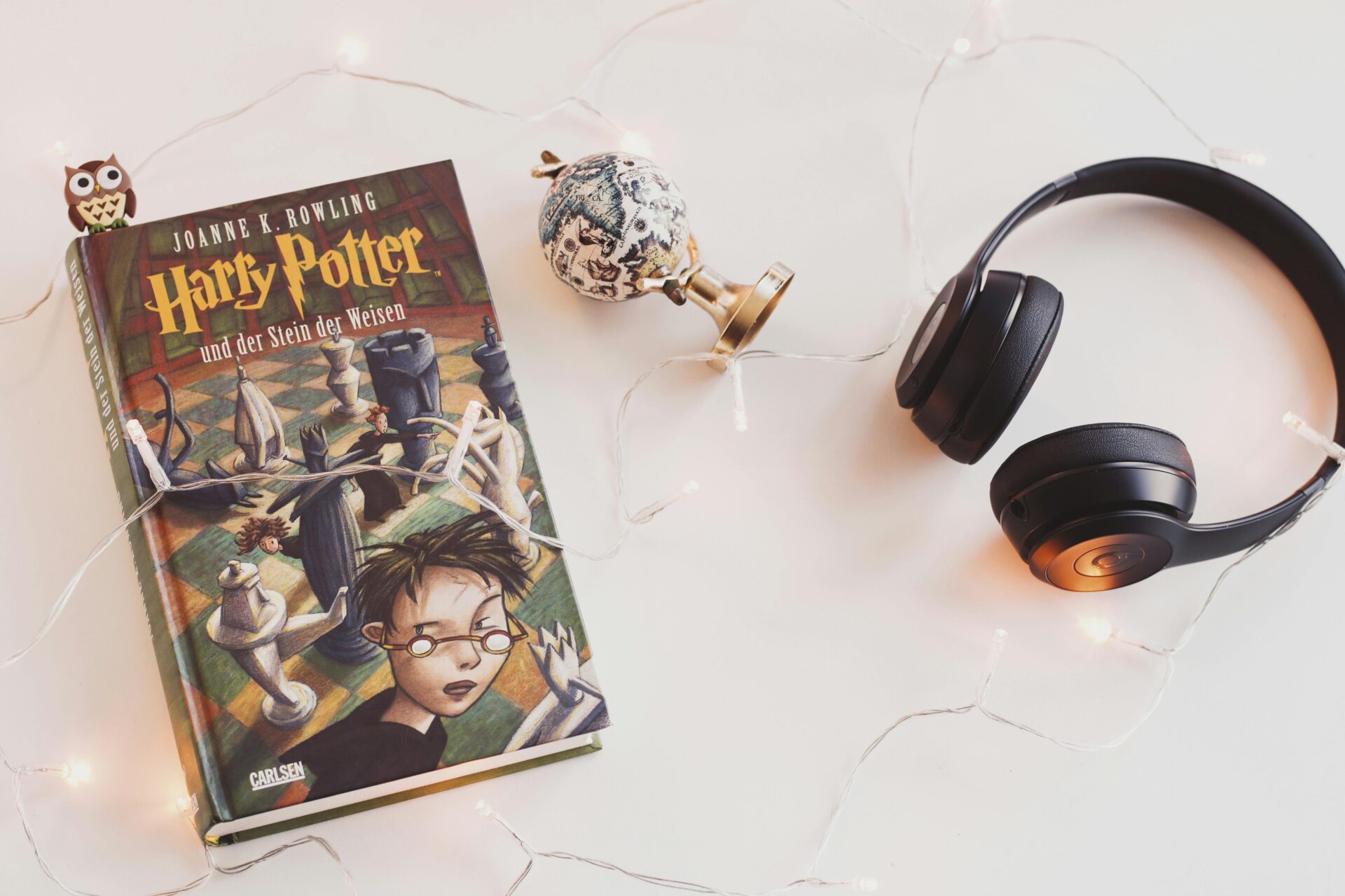 Minimalist setup with Harry Potter book, headphones, and string lights for a cozy reading experience.