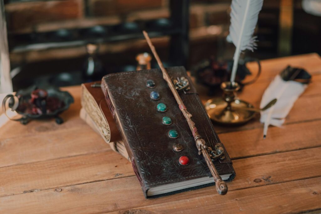 A wizard's desk featuring a spell book with gemstones, magical wand, and quill.